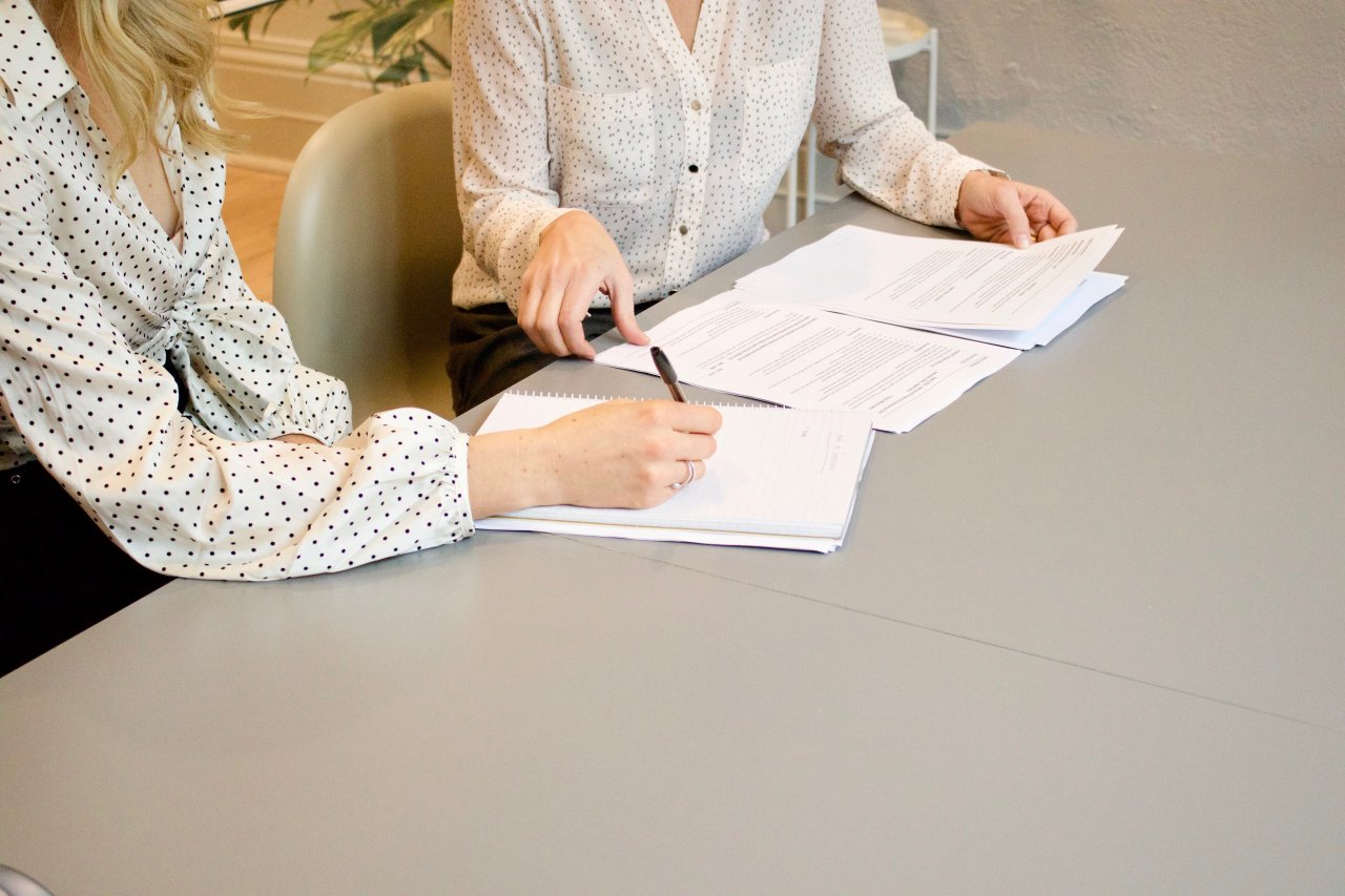 Two woman signing and going over paperwork.
